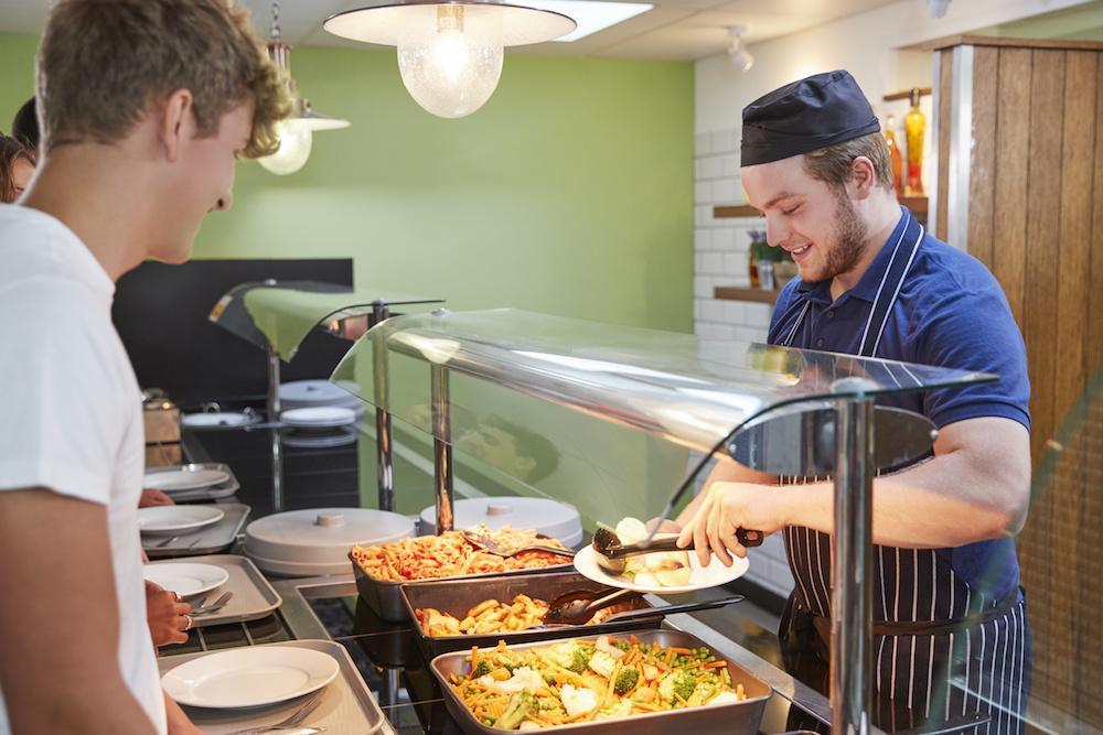 Restaurant collectif : serveur remplissant une assiette devant un étudiant